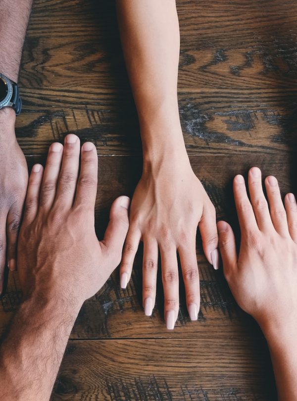 five human hands on brown surface